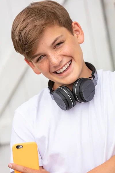 男の子ティーン男性子供外で彼の携帯電話と音楽やソーシャルメディアのためのブルートゥースワイヤレスヘッドフォンを使用して — ストック写真