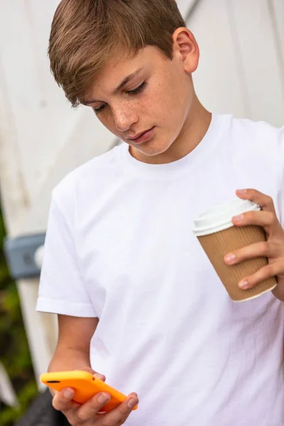 男の子ティーン男性子供外で彼の携帯電話を使用してお茶やコーヒーを飲む — ストック写真
