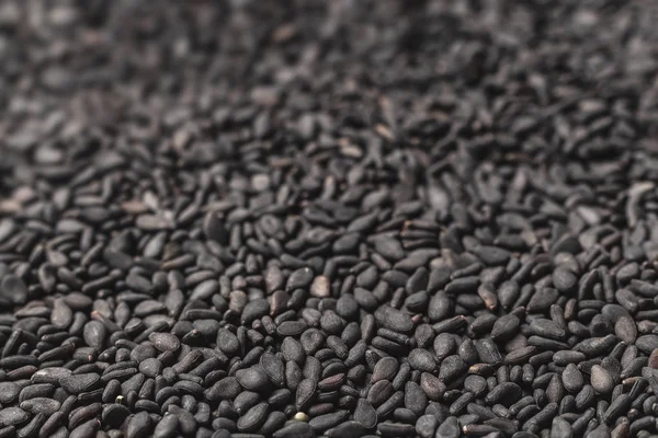 Black sesame seeds. Background from black beans turning into soft focus. Additives to eat - sesame seeds. Healthy food.