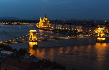 Budapeşte - Tuna Nehri ile şehrin gece panoraması. Budapeşte'nin bir bölümünün turistik manzarası. Tuna Nehri ve görünür parlamento ile gece şehir manzara.