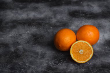 Turuncular koyu bir arka plan üzerinde yatıyor. Metin için boş alan. Olgun, sulu narenciye.