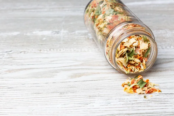 Kurutulmuş sebzeler, tahta bir tezgahta. Kurutulmuş sebze ve baharatlar ile Kavanoz. Kavanozdan dökülen baharatlar.