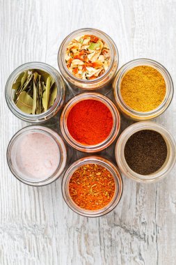 Kavanozlarda renkli baharatlar ve kurutulmuş sebzeler. Mutfak tezgahında duran baharat karışımları.