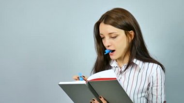 Düşünme ve gri arka plan üzerinde Hd Studio günlüğü yazma güzel genç iş kadını.