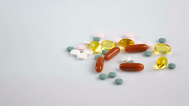 Beyaz bir arka plan üzerinde renkli parlak hap. Vitaminler beyaz bir yüzeye düşen