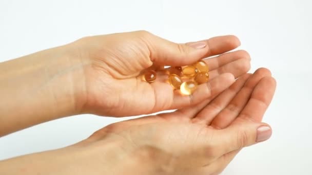 Tabletter, vitaminer på händerna. På en vit bakgrund, ljusa gula genomskinliga vitaminer. Medicin och hälsovård, Omega 3-fetter — Stockvideo