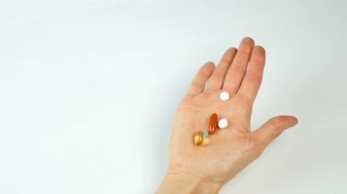 Parlak tabletler ve katkı maddelerinin beyaz zemin üzerinde bir el. Tıp ve Eczacılık. Sağlıklı beslenme, sağlıklı yaşam tarzı