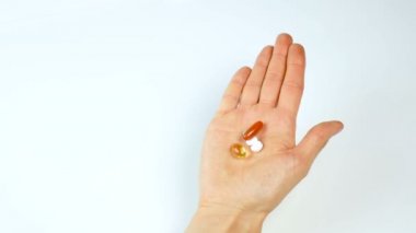 Parlak tabletler ve katkı maddelerinin beyaz zemin üzerinde bir el. Tıp ve Eczacılık. Sağlıklı beslenme, sağlıklı yaşam tarzı