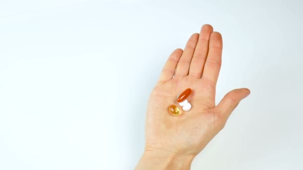 Heldere tabletten en additieven in een vrouwelijke hand op een witte achtergrond. Geneeskunde en farmacie. Gezond eten, gezonde levensstijl — Stockvideo