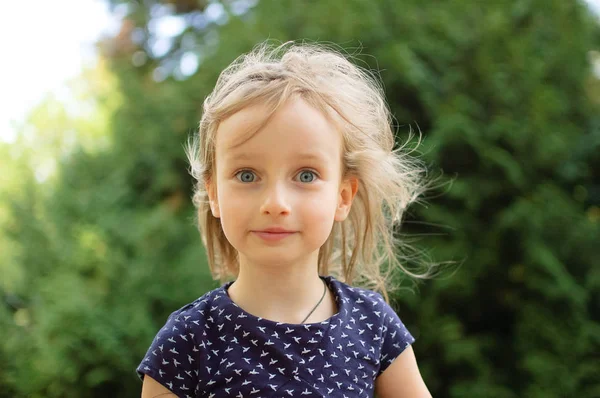 Primer plano Retrato de la linda niña rubia mirando a la cámara sorprendida durante el día de verano en el parque. Niño feliz al aire libre —  Fotos de Stock