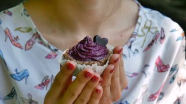 Menekşe küçük Cupcake açık havada tutan eller küçük kalp çikolata ile dekore edilmiştir. Yemek ve tatlılar. Leziz yemek tatlı.