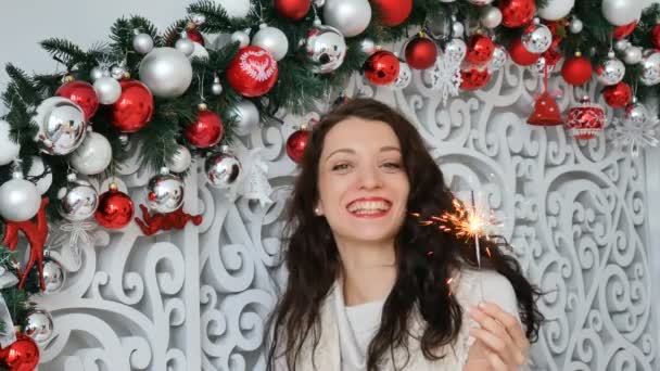 Mulher bonita com brilhos sobre fundo colorido. Closeup retrato de beleza de menina segurando sparklers sobre fundo vermelho prata. Jovem bela mulher celebrando véspera de anos novos — Vídeo de Stock