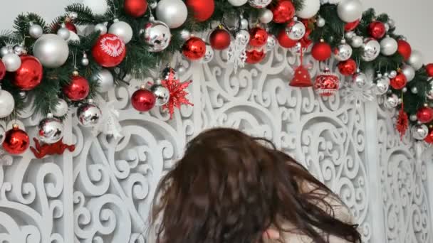 Retrato de una morena rizada brillante sobre el fondo de la decoración navideña con bolas plateadas y oscuras — Vídeos de Stock