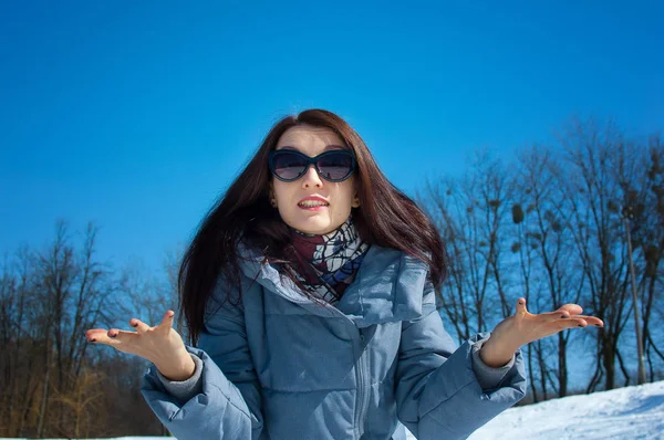 Förvånad över känslomässiga kvinna i solglasögon utomhus i stadsparken under blå himmel under tidigt våren — Stockfoto