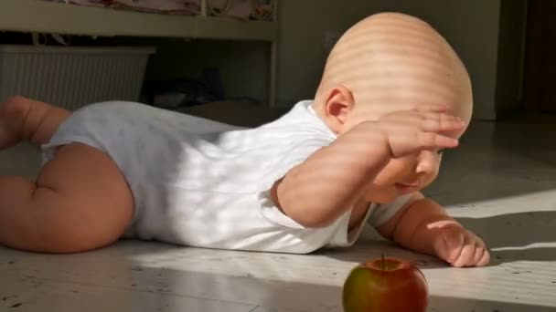 Reactie een zes maanden oude babyjongen met apple liggend op de vloer — Stockvideo