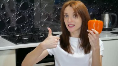 Şirin duygusal genç kadın mutfağa evinde oturan başparmak gösterilen büyük portakal dolmalık biber ile