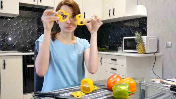 Щаслива молода жінка тримає свіжі шматочки болгарського перцю під час приготування вегетаріанської страви на кухні . — стокове відео