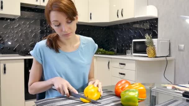 Jeune fille coupant poivron jaune frais à l'aide d'un couteau dans la cuisine. Mode de vie sain et concept de régime — Video