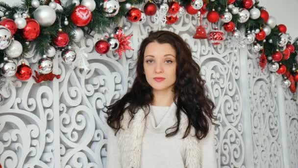 Retrato interior de hermosa morena joven en sombrero de santa rojo en estudio decorado de Navidad — Vídeos de Stock