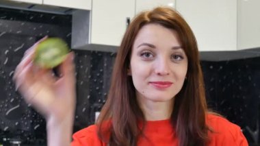 Kivi prepearing yemek sırasında iki yarısı ile mutfakta oynarken çekici duygusal genç kadın. Sağlıklı yaşam konsepti.