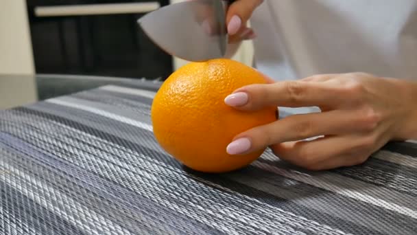 Joven hembra manos corte maduro jugoso naranja en la mesa en la cocina en casa — Vídeos de Stock
