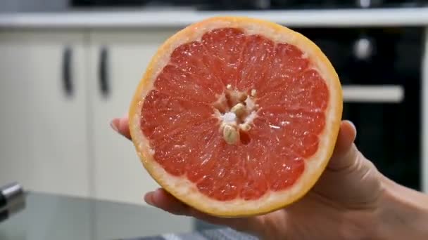 Vrouwelijke hand tonen een vers helft van grapefruit op de camera. — Stockvideo