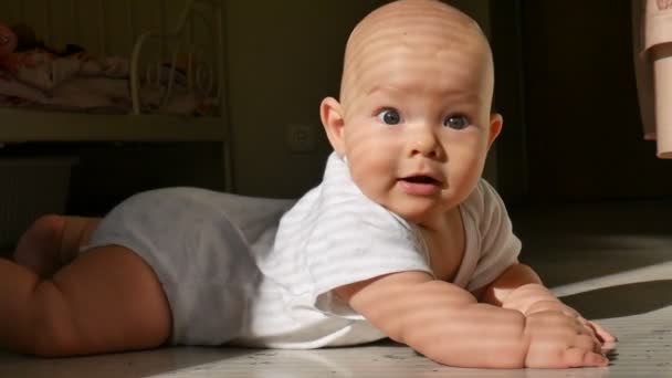 Bambino senza peli sdraiato sul pavimento e guardando la fotocamera con sorriso senza denti — Video Stock