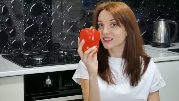 Güzel heyecanlı genç kadın mutfağa evinde oturan başparmak gösterilen büyük kırmızı dolmalık biber ile — Stok video