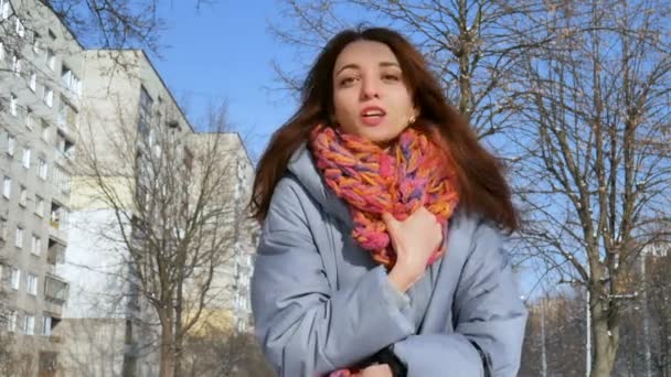 Close up retrato da menina adulta sorridente em casaco azul e cachecol de malha colorido durante o início da primavera na cidade — Vídeo de Stock