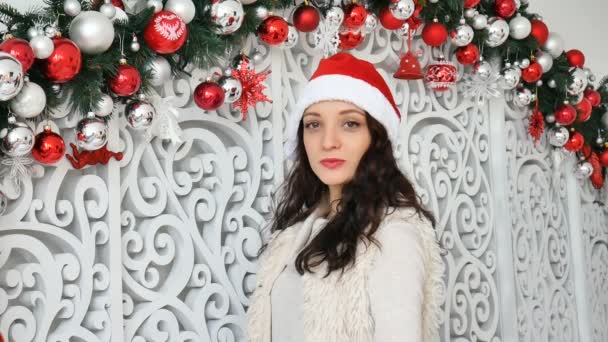Morena atraente com cabelos longos fazendo beijo de ar e sorrindo olhando para a câmera no fundo decorado de Natal — Vídeo de Stock