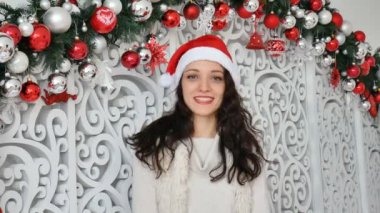 Çok gülümseyen genç kadın kırmızı santa şapka Noel kameraya bakarak içinde portre stüdyo dekore edilmiş