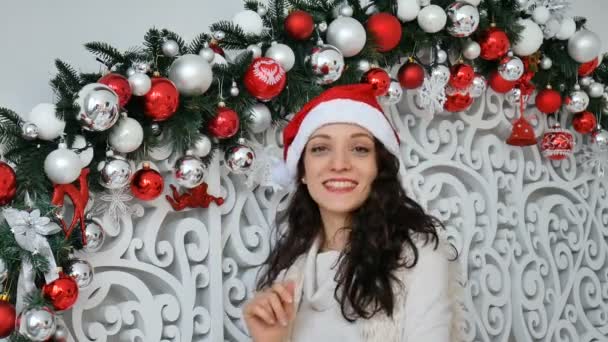 Hermosa mujer joven con el pelo rizado oscuro está tocando bolas de Navidad blancas y rojas en el estudio decorado y sonriendo — Vídeos de Stock