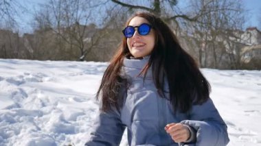 Yetişkin kız mavi yansıtılmış güneş gözlüğü ve düz saçlar oynama ve açık havada bahar sırasında parkta gülüyor kartopu atarak gülümseyerek. Açık havada faaliyetleri kavramı
