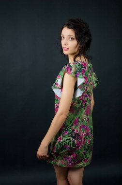 Pembe çiçekler ile yeşil elbise siyah arka planda stüdyoda poz beautuful genç kız arka görünümü