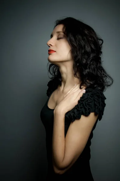 Sexy brünette Frau mit roten sinnlichen Lippen posiert auf schwarzem Hintergrund mit geschlossenen Augen zum Vergnügen — Stockfoto