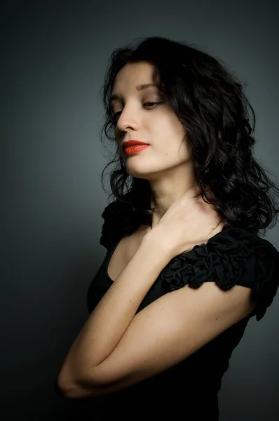 Sexy brünette Frau mit roten sinnlichen Lippen posiert auf schwarzem Hintergrund mit geschlossenen Augen zum Vergnügen — Stockfoto