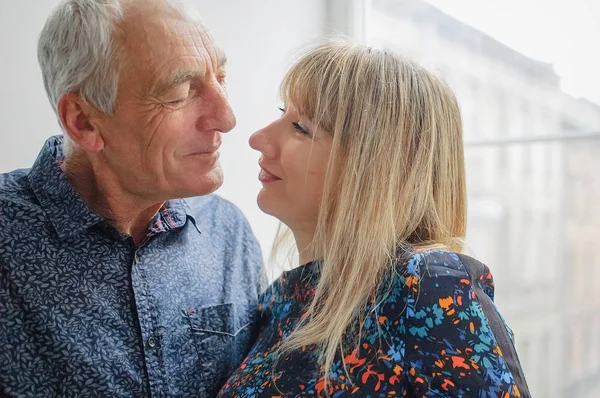 Atractiva mujer rubia abrazando al apuesto hombre mayor y mirándolo con amor y pasión en sus ojos. Pareja con diferencia de edad . —  Fotos de Stock