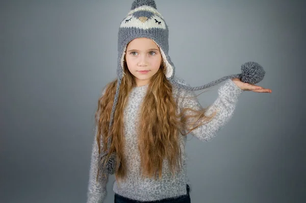 Bela menina adolescente sorridente com cabelo longo em um chapéu de inverno - em fundo cinza-prata — Fotografia de Stock