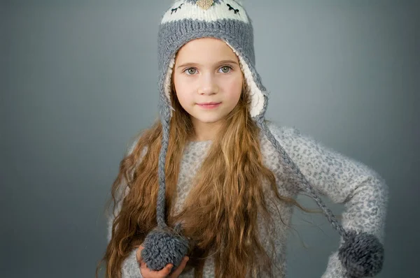 Beautiful smiling teenage girl with long hair in a winter hat - on gray-silver background — Stock Photo, Image
