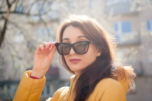 Modelo feminino bonito com lábios sensuais na jaqueta amarela vestindo óculos escuros na moda . — Fotografia de Stock