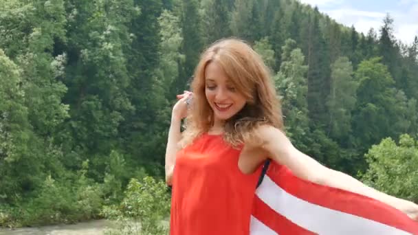 Férias patrióticas. Mulher emocional feliz com bandeira americana no fundo da floresta verde durante o dia de verão ao ar livre. EUA celebram 4 de julho . — Vídeo de Stock