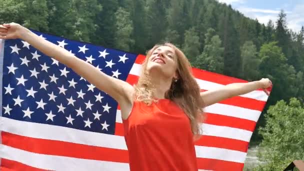 Retrato de una hermosa niña con un vestido rojo sobre el fondo de las montañas del bosque y el cielo. Día de la independencia de Estados Unidos, día patriótico — Vídeos de Stock