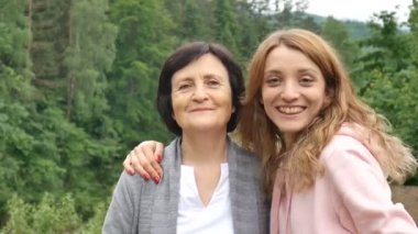 Onun yetişkin kızı sarılma ve kameraya bakarak ile gülümseyen mutlu kafkas kıdemli anne Açık yakın portre