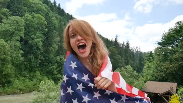 Retrato de uma menina bonita em um vestido vermelho contra o fundo das montanhas da floresta e do céu. Dia da independência dos EUA, dia patriótico — Vídeo de Stock