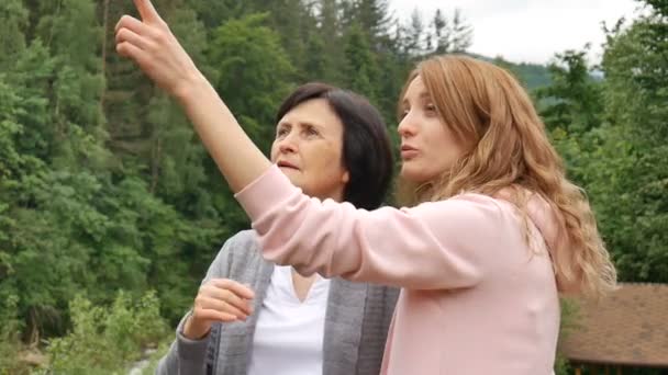 An elderly retired mother and adult daughter are talking against the background of wooded mountains. Holidays in the mountains, mothers day, two generations — Stock Video