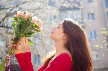 Sevimli genç kadın renkli çiçekler büyük bir buket aldı ve o sadece erken bahar sırasında dışarıda zaman harcama bakıyor.