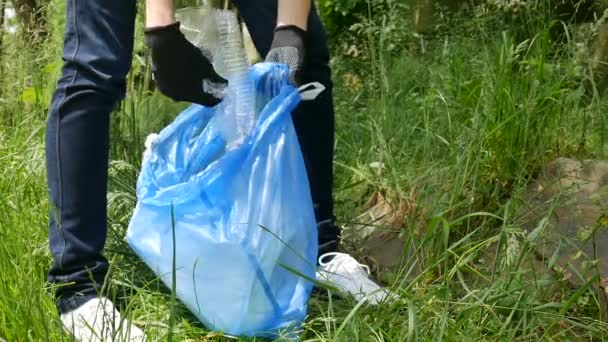 Mãos femininas coletando lixo plactic no pacote azul. Limpeza da natureza, ecologia voluntária, conceito verde . — Vídeo de Stock