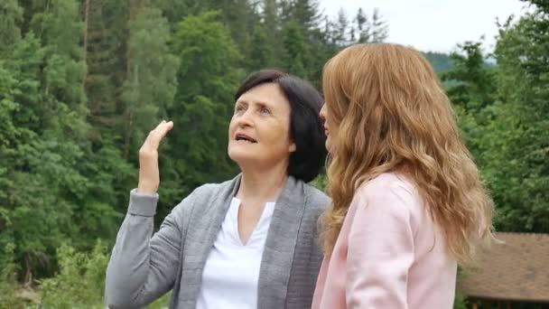 Une mère retraitée âgée et une fille adulte parlent dans le contexte des montagnes boisées. Vacances à la montagne, fête des mères, deux générations — Video