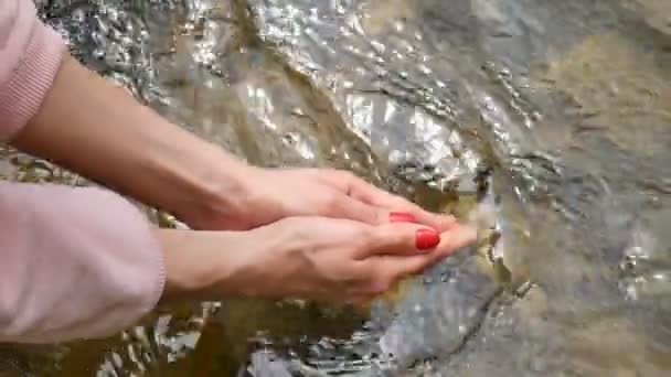 Woman holding in hand a yoni egg. Rose quartz crystal egg on river background. Female health concept — Stock Video