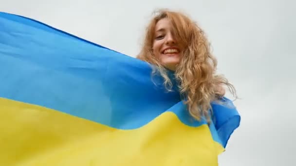 Feliz chica joven emocional con azul y amarillo bandera de Ucrania sobre el fondo del cielo — Vídeo de stock